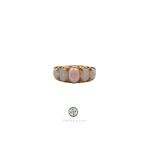 An opal ring with gold vermeil plating on a silver base, featuring a central opal stone surrounded by smaller clear crystals set in a gold-colored band.