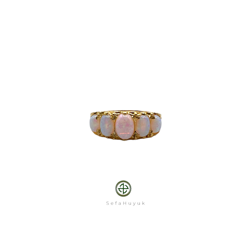 An opal ring with gold vermeil plating on a silver base, featuring a central opal stone surrounded by smaller clear crystals set in a gold-colored band.