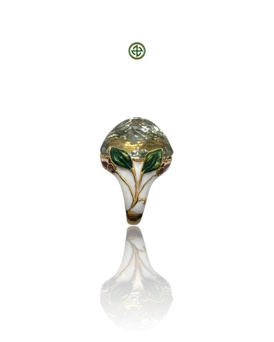 An ornate silver ring featuring a green amethyst center stone with enamel details, displayed against a white background.