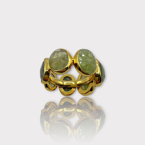 A gold-colored eternity ring with green tourmaline stones set in a silver band, viewed from the side.