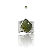 A green tourmaline gemstone set in a sterling silver ring with a white rhodium finish.