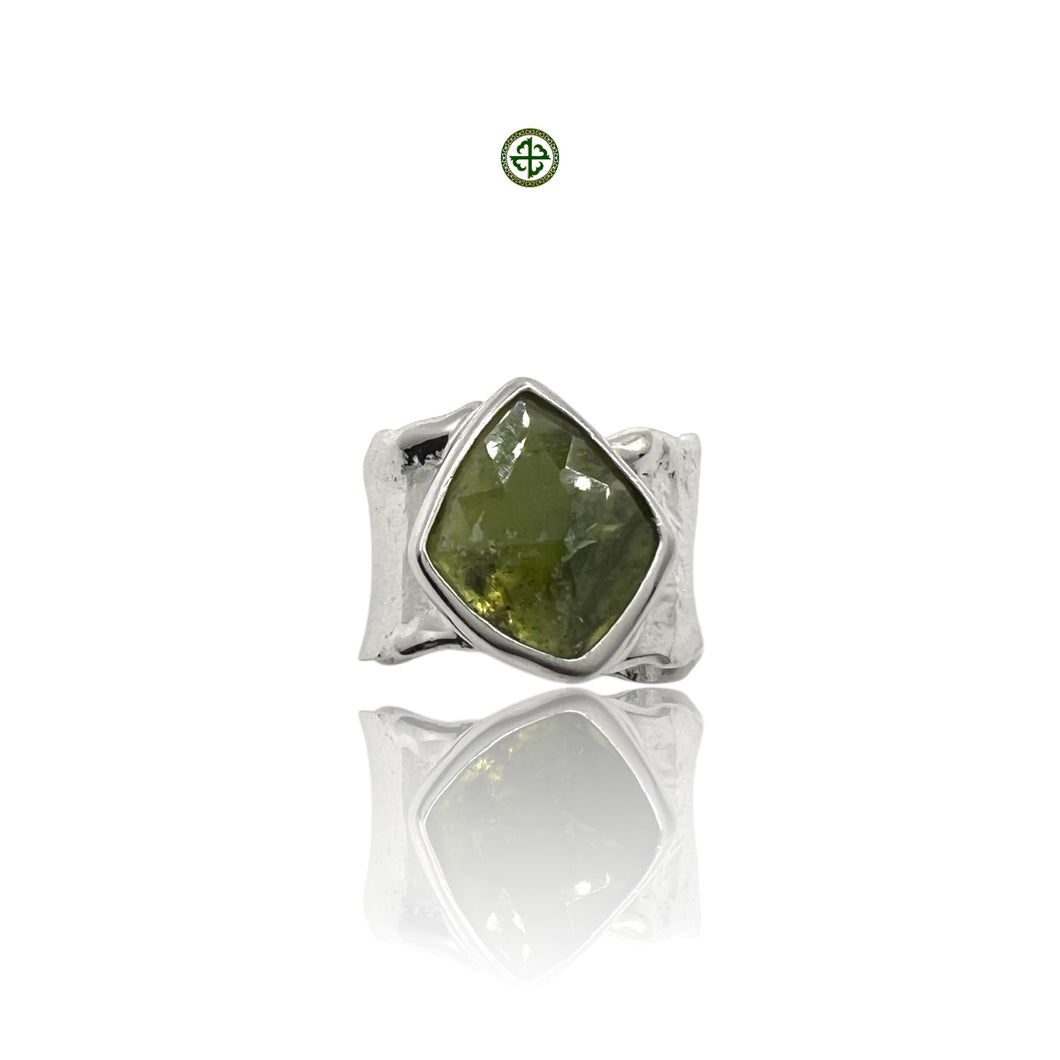 A green tourmaline gemstone set in a sterling silver ring with a white rhodium finish.