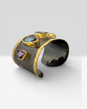 Luxury wide cuff bangle crafted from black rhodium plated 925 sterling silver with thick 18K gold vermeil. Featuring Green Amethyst, Kyanite, Tourmaline, Blue Topaz and Amethyst gemstones. Adjustable statement bracelet for 16–18 cm wrists.
