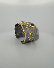Luxury gemstone cuff bangle crafted in black rhodium plated 925 sterling silver with thick 18K gold vermeil. Featuring Green Tourmaline, Amethyst, Lemon Quartz, Smoky Quartz and Yellow Tourmaline. Adjustable statement bracelet for 16–17 cm wrists.