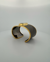 Luxury green amethyst cuff bangle crafted in black rhodium plated 925 sterling silver with thick 18K gold vermeil bezel. Elegant wide statement bracelet adjustable for 16–17 cm wrists.
