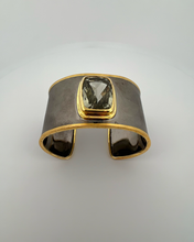 Luxury green amethyst cuff bangle crafted in black rhodium plated 925 sterling silver with thick 18K gold vermeil bezel. Elegant wide statement bracelet adjustable for 16–17 cm wrists.
