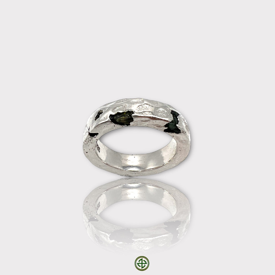 A silver band ring featuring a raw black tourmaline gemstone, with a visible textured finish on the metal.
