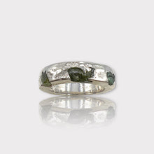 A silver band ring featuring a raw, uncut peridot gemstone with a textured finish.