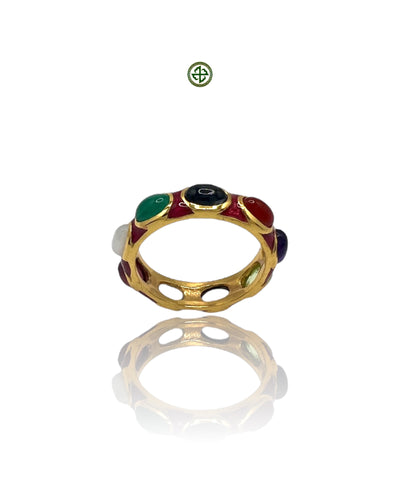 A gold-colored eternity ring with multiple colorful gemstones and red enamel accents, displayed against a white background.