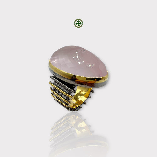 A rose quartz statement ring with a gold and black rhodium plating, displayed against a white background.