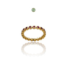 A gold-colored band ring with round cut ruby stones arranged in a stacking design.