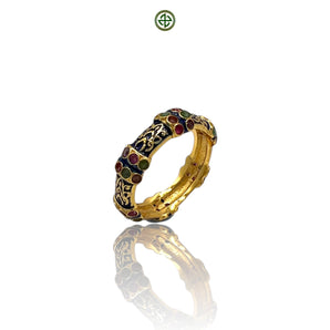 A gold vermeil ring with navy blue enamel and alternating ruby, emerald, and amethyst stones set around the band.