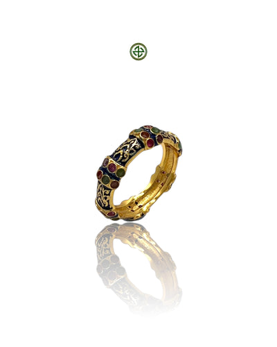 A gold vermeil ring with navy blue enamel and alternating ruby, emerald, and amethyst stones set around the band.