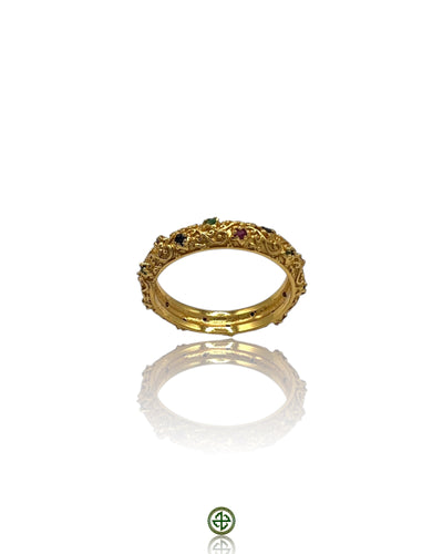 A gold-colored eternity ring with alternating ruby, emerald, and sapphire stones set in a continuous band.