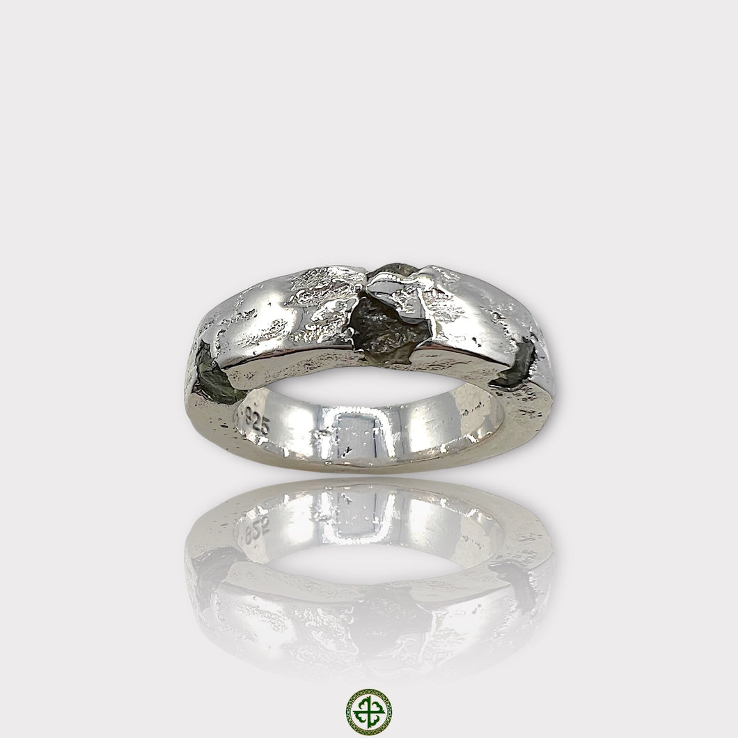 A silver ring featuring a raw peridot gemstone with a textured band.