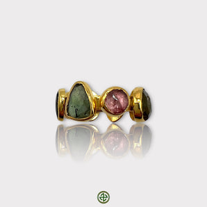 A multicolored tourmaline stone set in a gold-colored band, designed as an eternity ring.