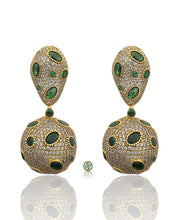 Pair of gold earrings with green gemstones on a white background