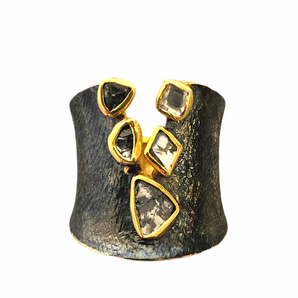 A black rhodium-plated band ring with gold vermeil trimmings, featuring a line of raw diamonds.